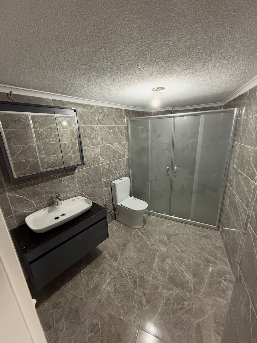 Gri mermer kaplı banyo ve cam duş kabini